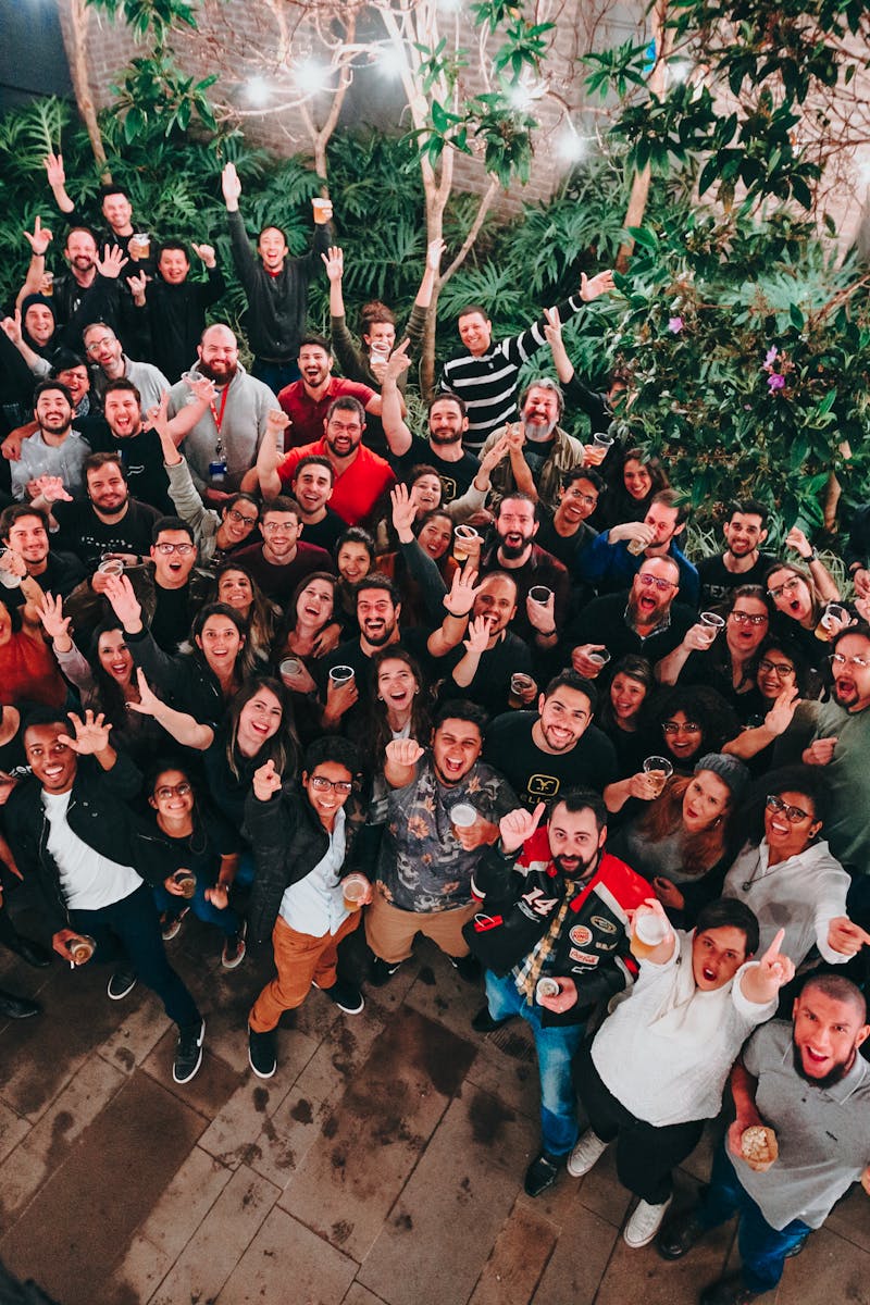 A large group of joyful people posing under string lights in a garden setting. Perfect for joyful and community themes.